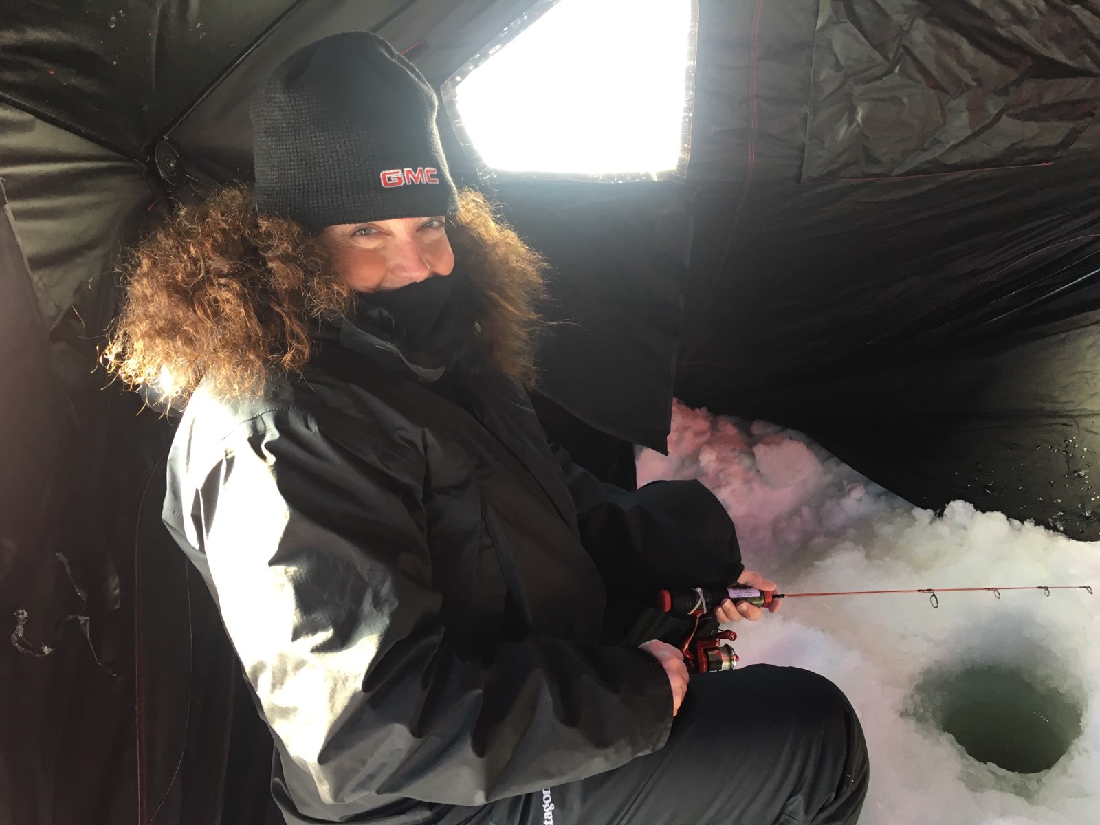 Woman in winter gear ice fishing