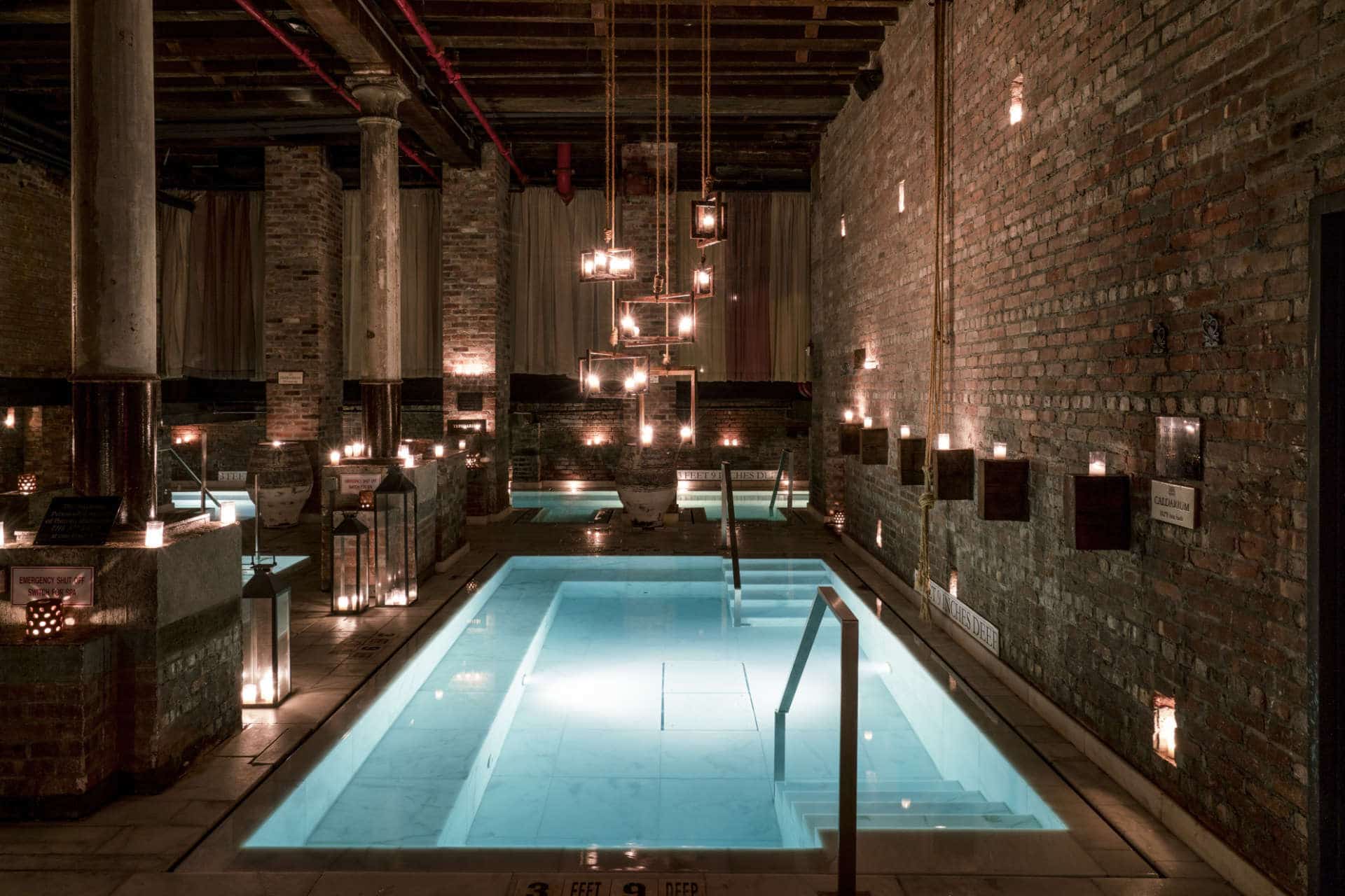 Industrial brick interior with illuminated pools at AIRE Ancient Baths, New York City