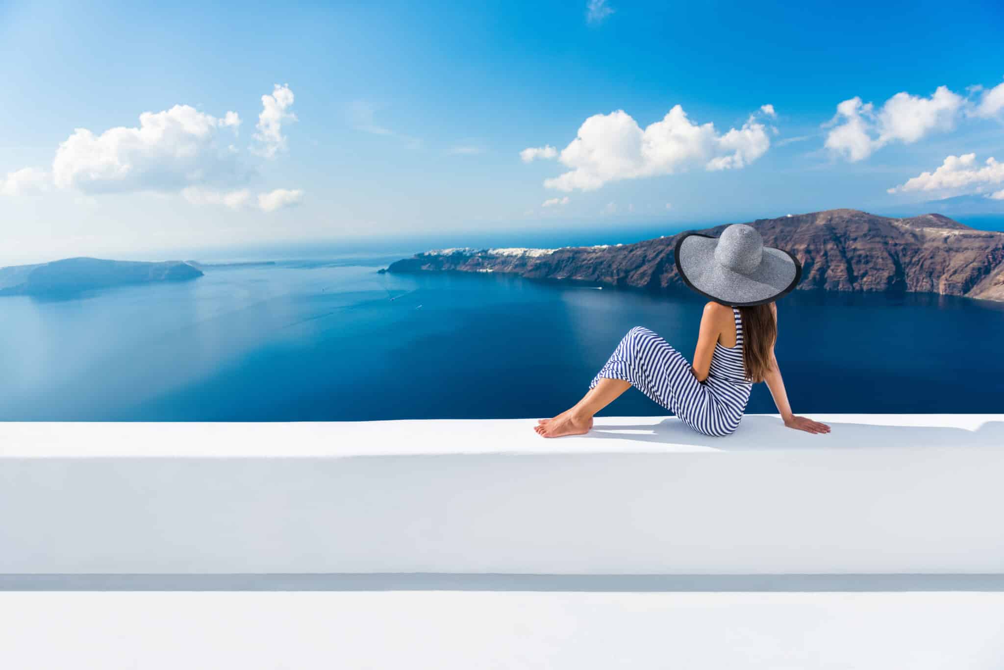 Fashionable woman on a white ledge overlooking the sea