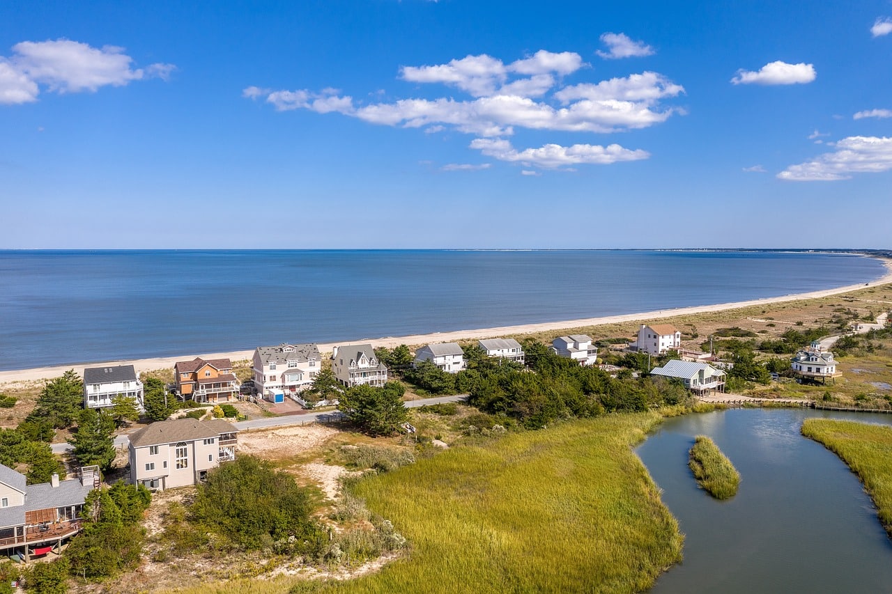 View of the long coastal beach, houses, trees, and a river in Delaware.