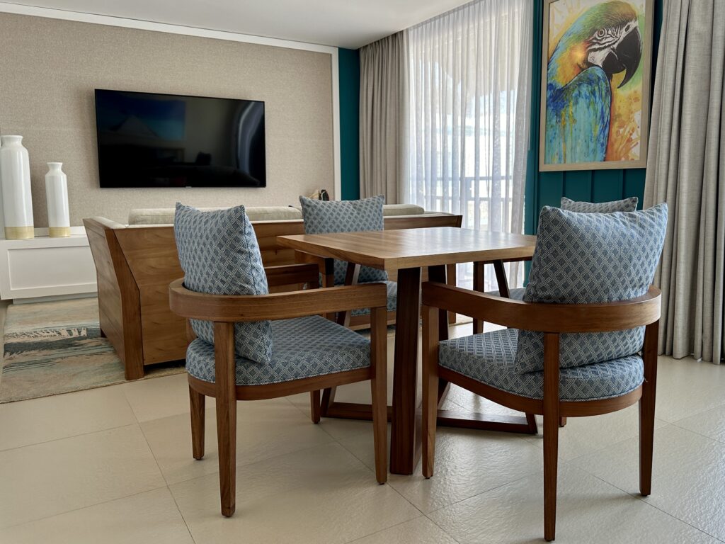Spacious living area with table and chairs and sofa with wall mounted tv at the Margaritaville Cancun.