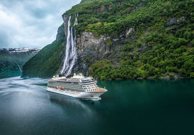 cruise ship sailing by waterfall in Norwegian Fjord