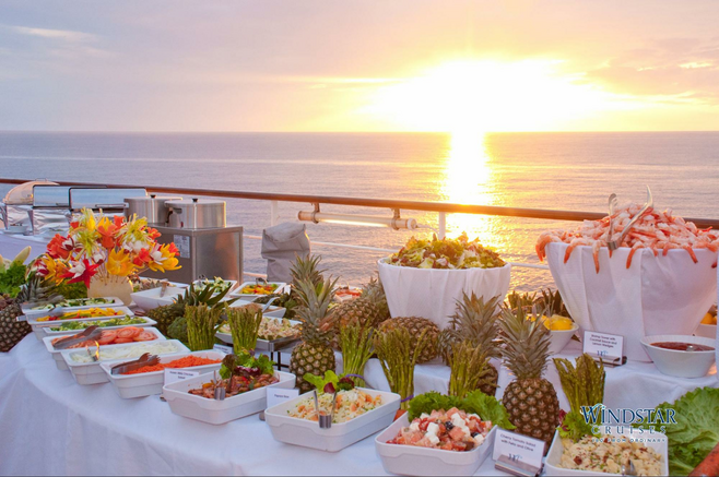 A spread of BBQ food on the deck of WIndstar Cruises ship at sunset