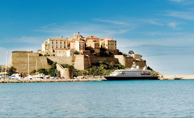 Cruise ship moored next to a Mediterranean style stone village 