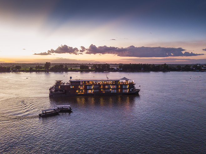 Aqua Expeditions' Mekong is met with little ferry boats on river at dusk.