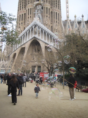 La Sagrada familia with bubbles, adults, and children walking around.