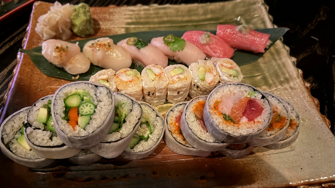 Plate of sushi with different rolls, raw fish, and vegetarian options.