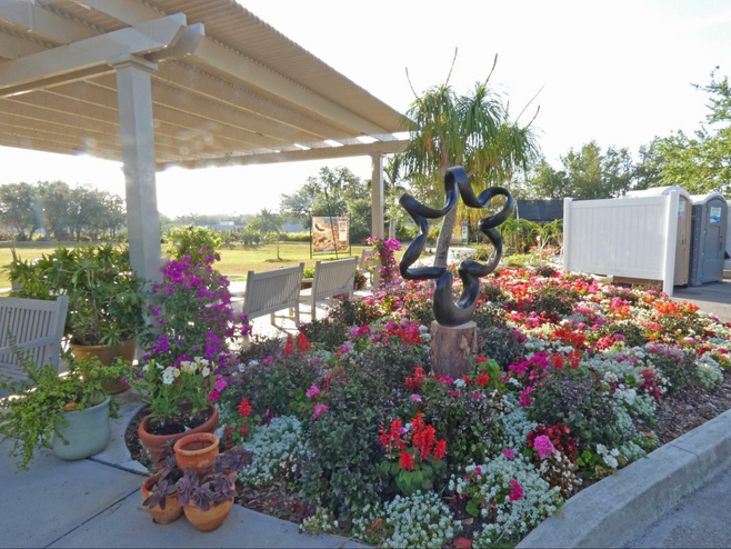 A bed of flowers with a sculpture in middle