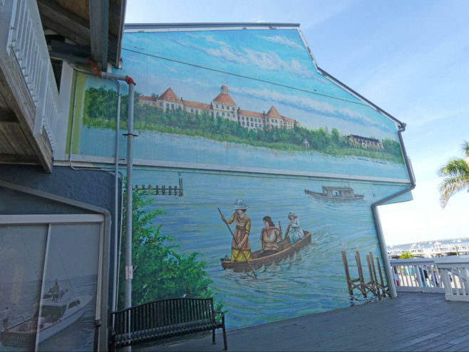 A mural showing three 19th century women rowing across Charlotte Harbor with a hotel in background.