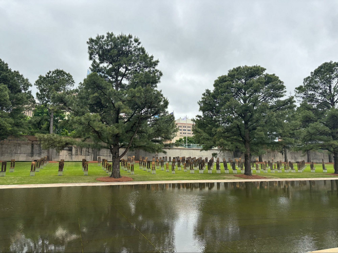 Empty chairs on a lawn with trees with a pond in the foreground