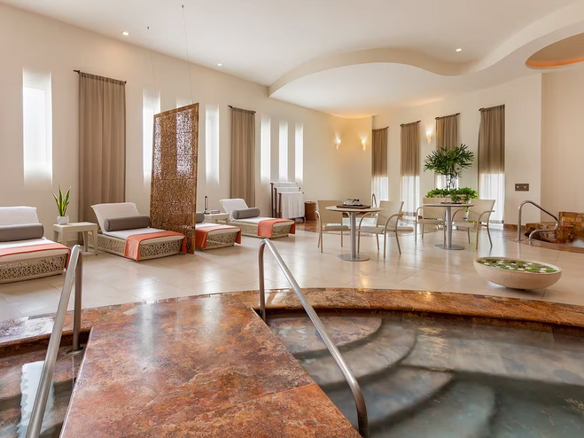 Indoor spa hot tubs, with lounge chairs in the background, and elongated windows