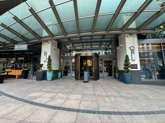 Hotel 1000 Seattle entrance. Large revolving door and planters with topiaries. Valet sign and sign for the All Water restaurant.