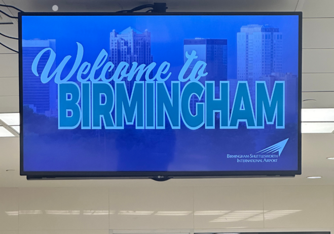Image of screen with "Welcome to Birmingham" at Birmingham Shuttlesworth Airport.