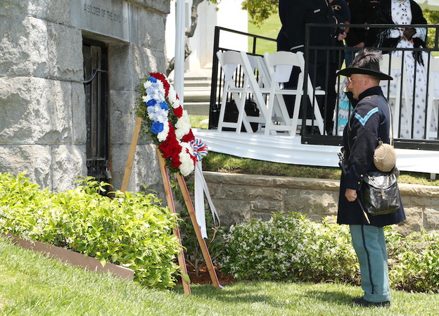 A service member stands in front of a memorial wreath at Forest Lawn cemetery.