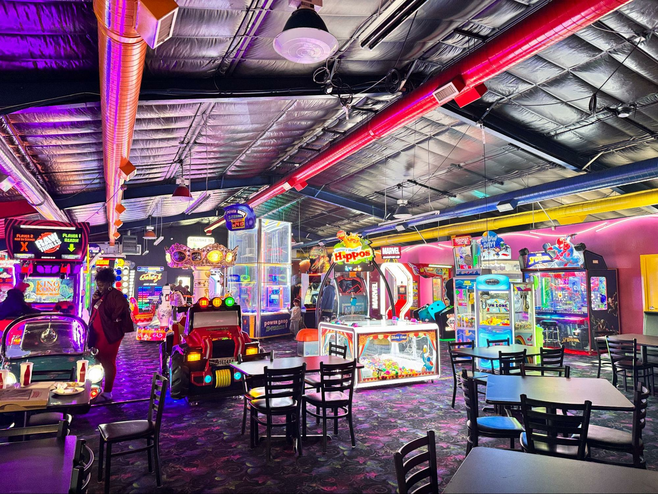 bright colored arcade room with games and tables with overhead duct work