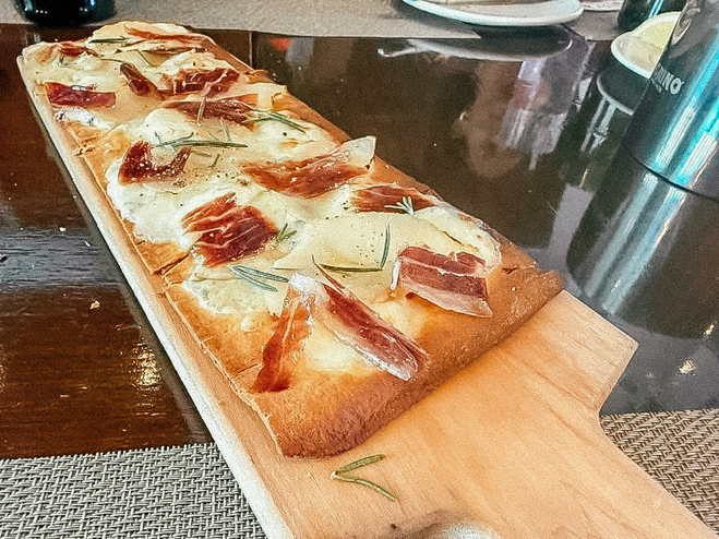 Flatbread pizza served on a wooden charcuterie board.
