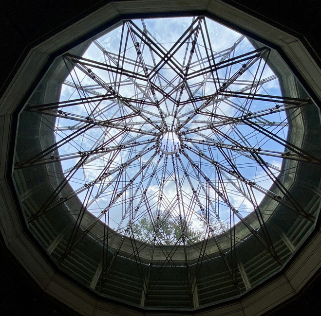 Blue sky visible through the top of a glass domed pavilion.