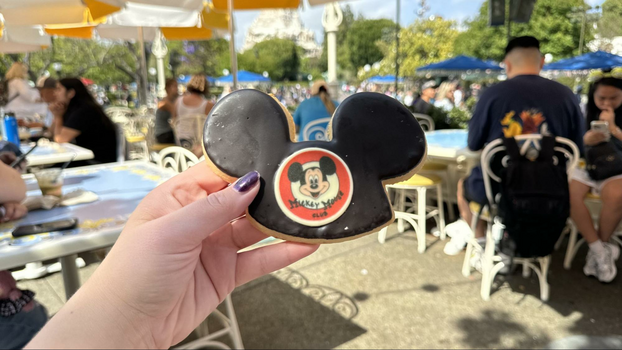 Mickey ear hat shaped cookie with black chocolate and a white chocolate emblem with an image of Mickey Mouse.