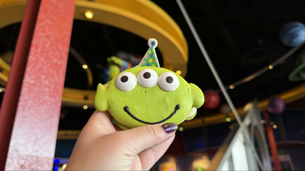 Green-shaped alien macaroooon with three candied eyes and a small chocolate celebration hat.