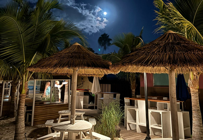 Palm umbrellas shelter outdoor dining under the stars as the moon rises at Beaches Resort in Turks & Caicos.