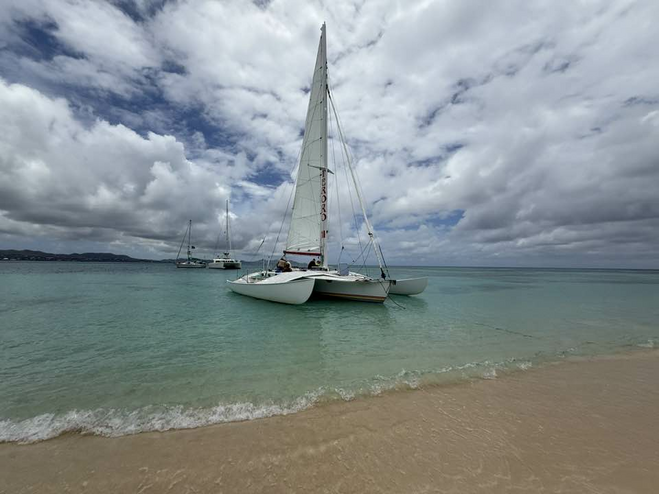 Catamaran on a sandy beach with blue water and a cloudy sky