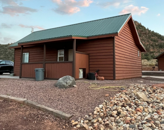 Rustic cabin under a blue sky with hills in the background.