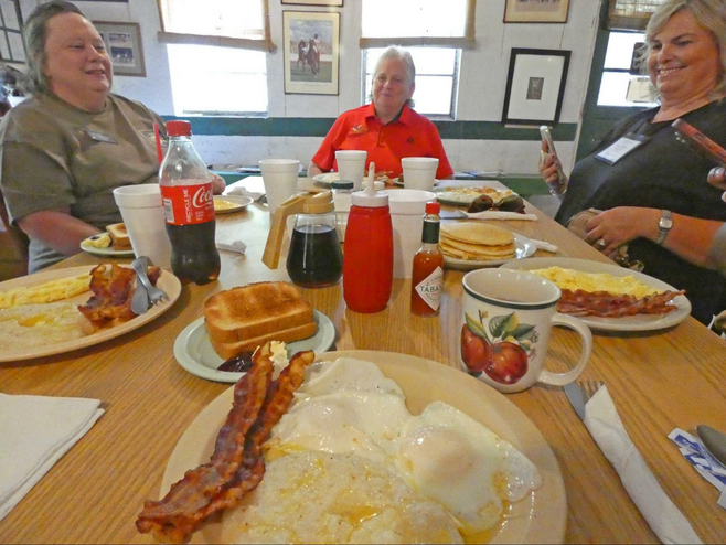 Three women at breakfast table with food.
