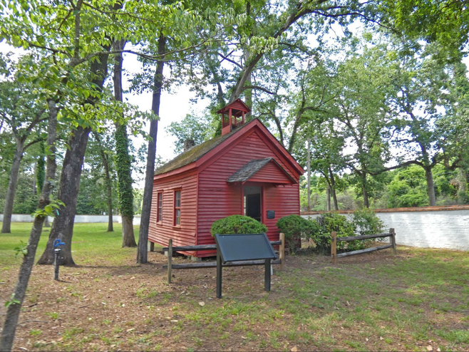 Red wood frame building with trees around it.