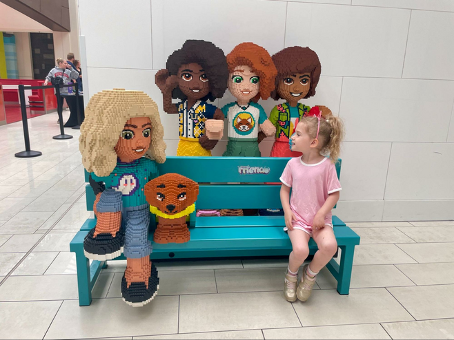 Girl sits on a bench outside of The LEGO Store at Mall of America