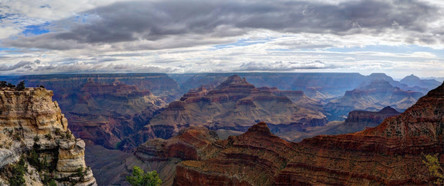 Colorful Grand Canyon wide view dappled in sunlight from overhead clouds.