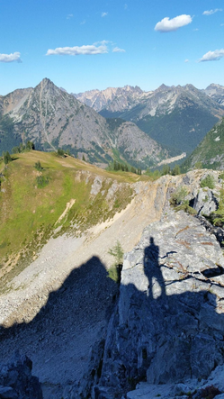 Hiker's shadow cast over trail following ridge line.