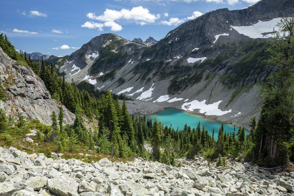 Looking down into rocky valley with turquoise blue lake at bottom.