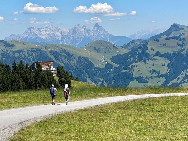 Two men walking down a path overlooking a mountain valley.