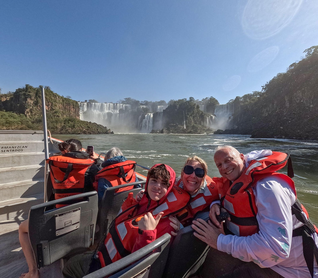 Family in a boat sailing up to water falls.