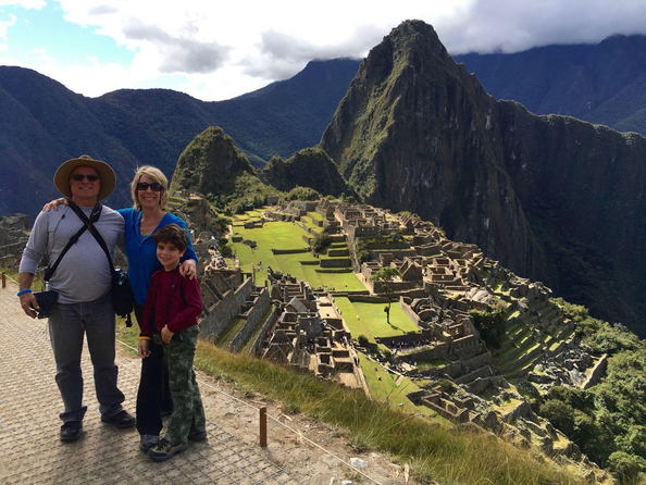 A family standing on a ledge overlooking Machu Picchu.