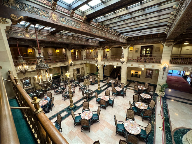 Plush chairs and marble tables with soaring two story ceiling with skylights and ornate carved wood.