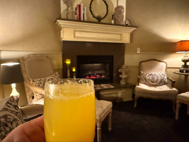 Handing holding a mimosa in a spa relaxation room with antique type chairs and a fireplace