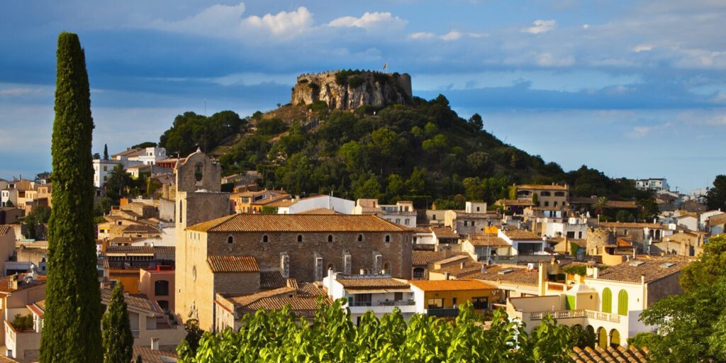 Ancient castle on steep hill that overlooks a city below.