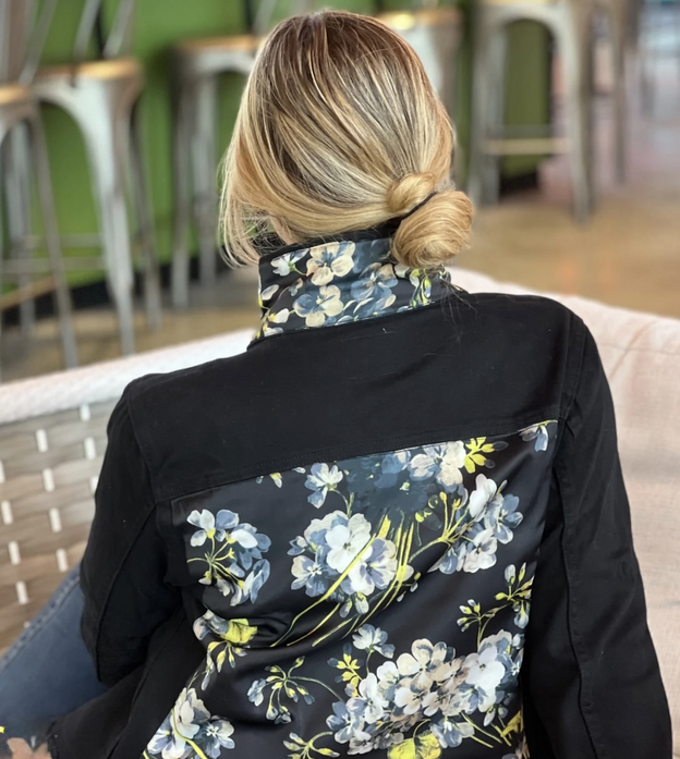 Closeup of a black denim jacket featuring a floral silk insert