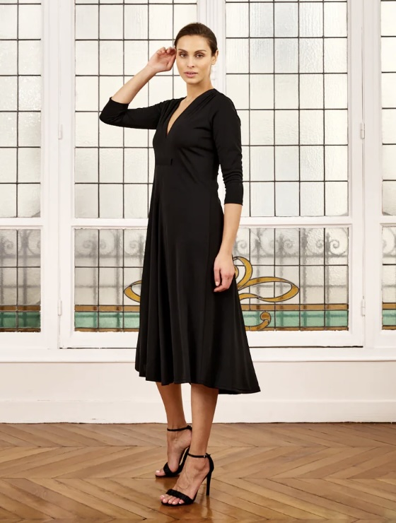 Woman wearing black sandals and black knit midi dress with a v-neck