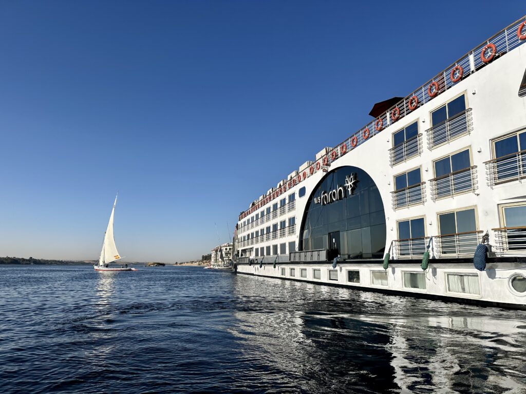 River cruise ship on the Nile in Egypt with a small sailing vessel in the background.