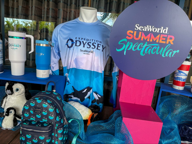 SeaWorld Orlando theme park branded merchandise in a display that includes t-shirts, backpacks, stuffed animals and beverage containers.
