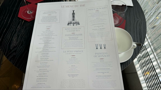 Print out of tea menu on table next to a white tea cup.