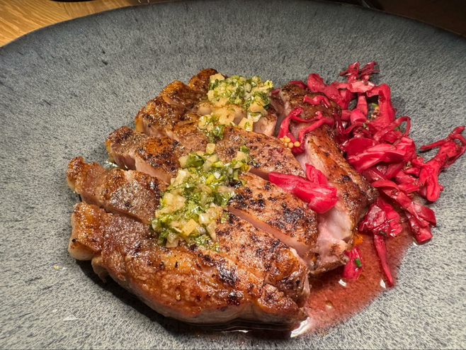 Large porkchop with chimichurri sauce and red cabbage.