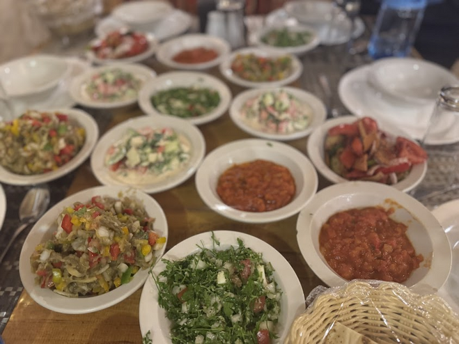 A selection of Jordanian foods, including tomato salads and eggplant dips in white bowls.