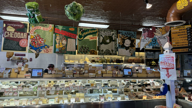 Wide case line filled with dozens of cheeses and vibrant posters hanging from the ceiling.