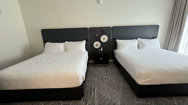 Two king beds on a geometric carpet with black headboards.