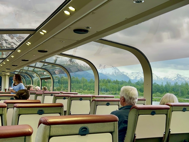 couple sit in dome car with giant window view