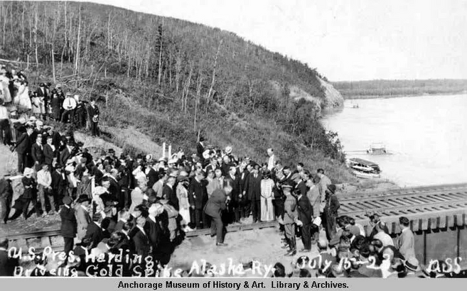 People gather on and near the tracks to watch President Warren G Harding drive a golden spike