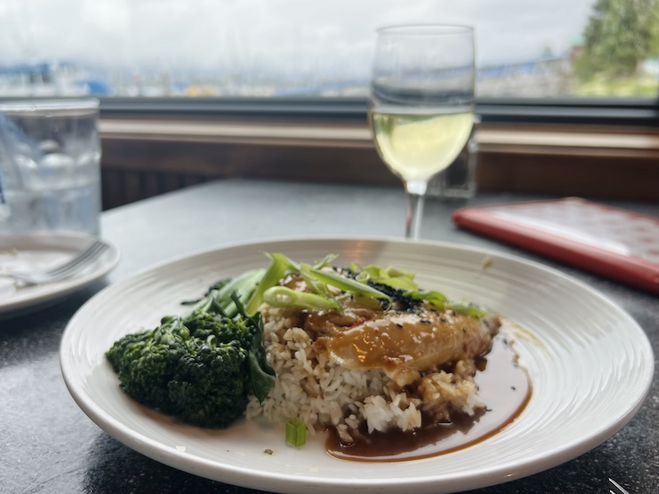 Chicken and rice plated dinner and wine with a view out the window